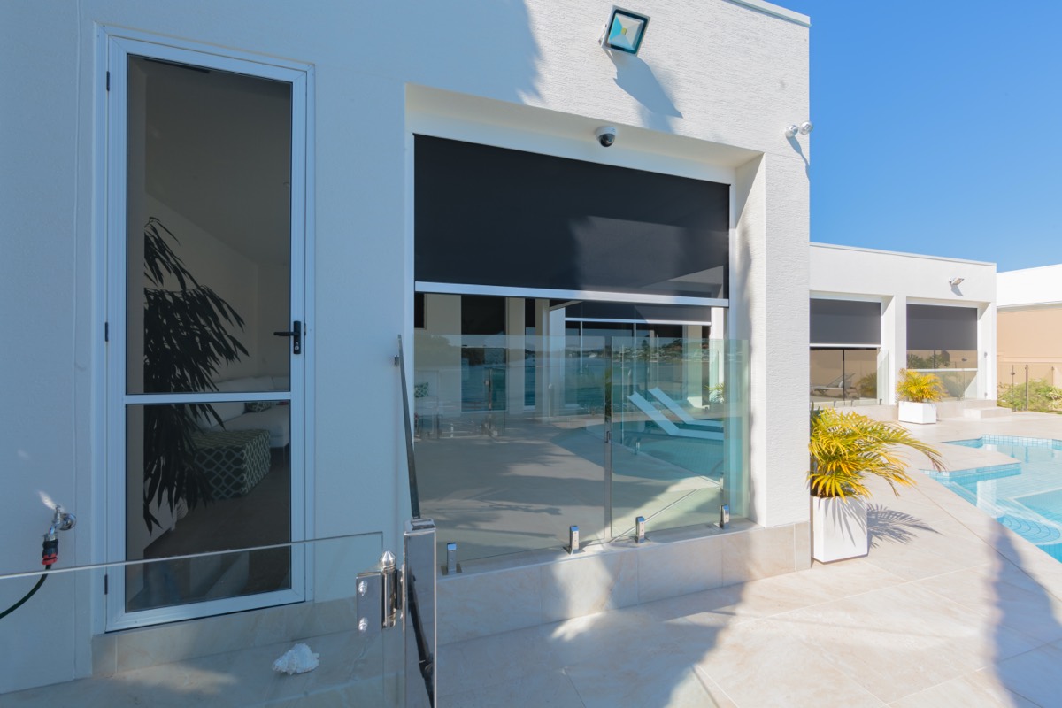 Zipscreen down over a door opening on the side of a white rendered house