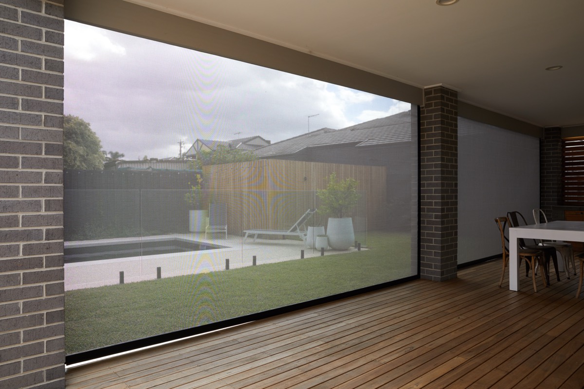 Looking out from inside through a dark Zipscreen mesh to the pool and timber deck