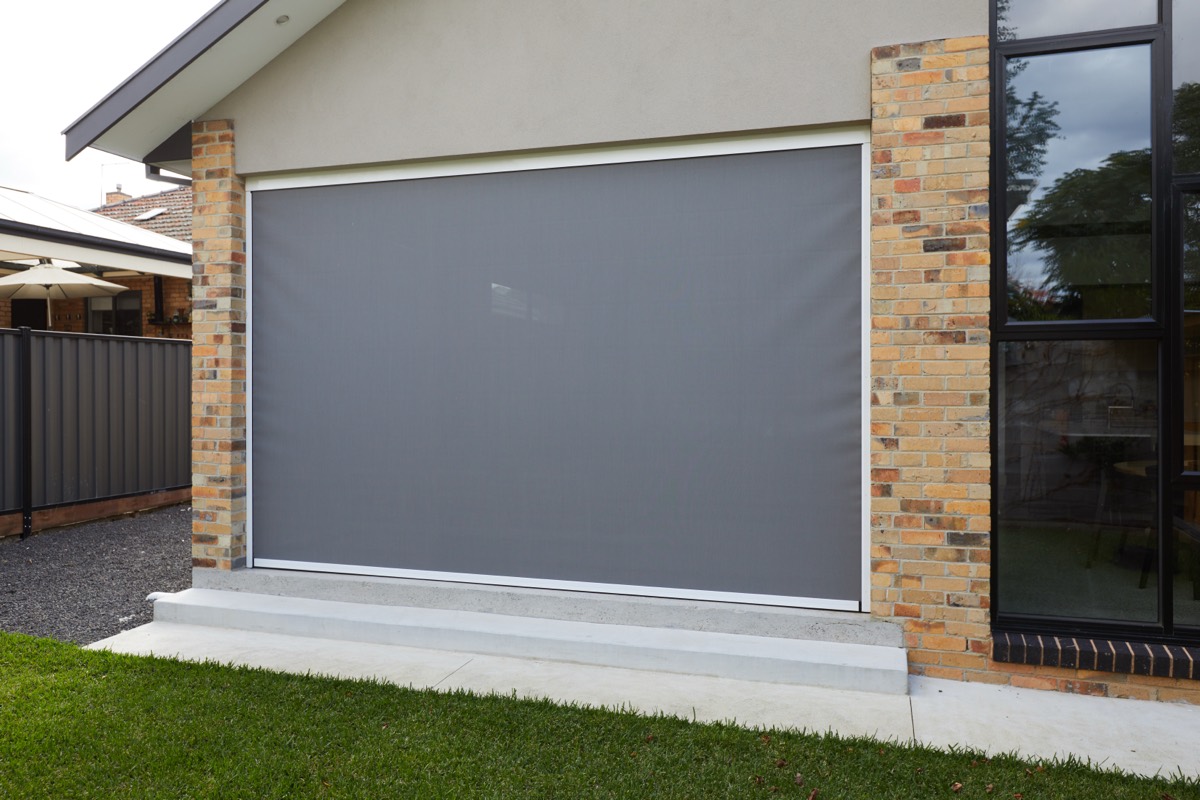 Single grey Zipscreen lowered between the brick pillars of a home on an overcast day